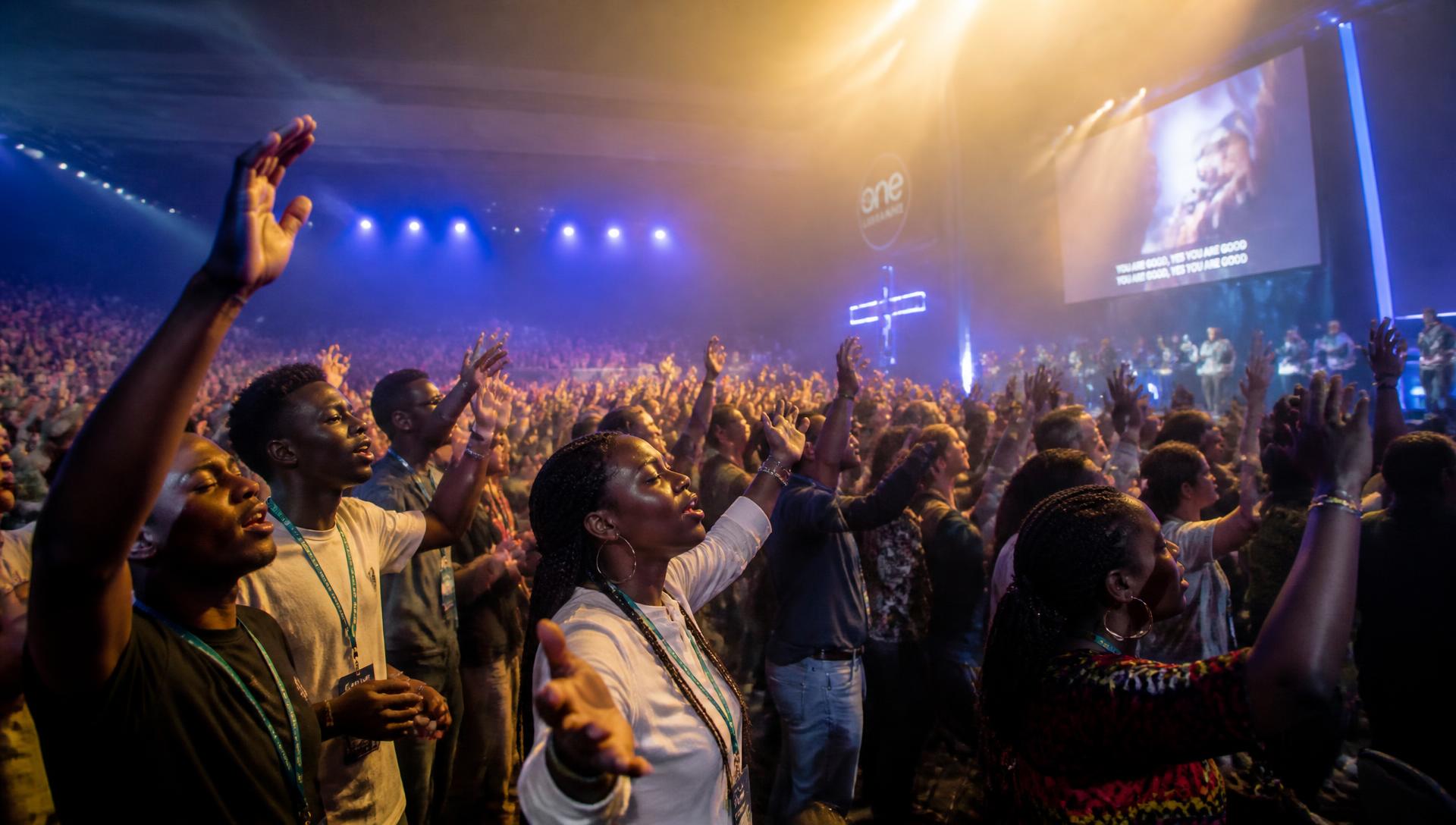 Young believers worshipping with hands raised at a WYGGF conference